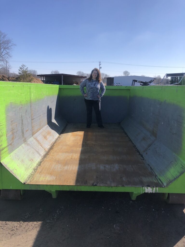 a woman standing in an empty 15 yard dumpster